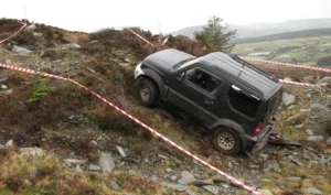 Black 4x4 vehicle driving up a steep track.