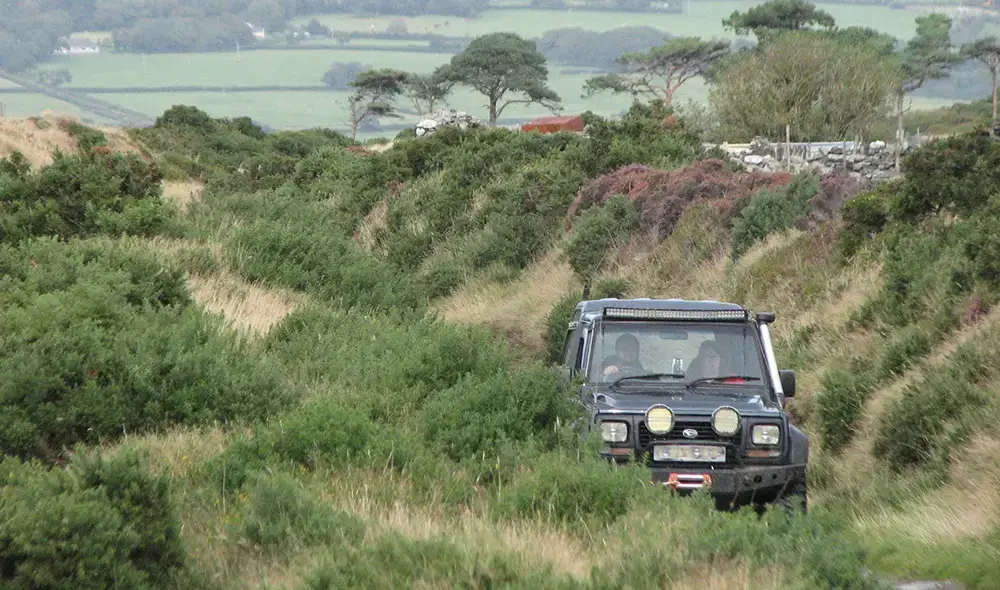 Land rover driving on a small track in the country.