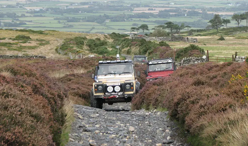 Land rovers on a lane run.