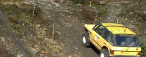 yellow range rover driving up a hill.